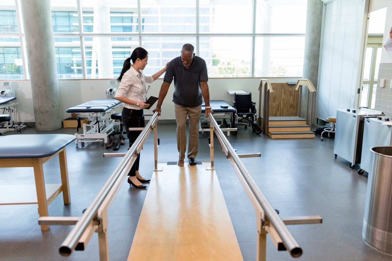 Caring female physical therapist helps stroke victim in rehab center